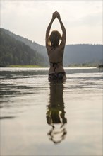 Caucasian woman standing in lake wearing bikini