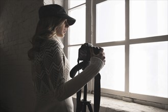 Caucasian woman near window holding camera