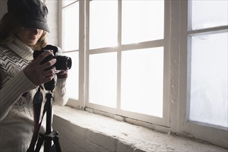 Caucasian woman near window photographing with camera