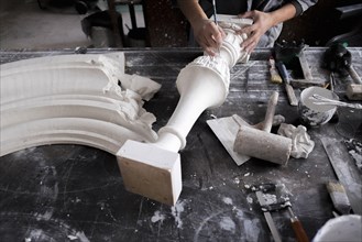 Hands of Caucasian sculptor carving plaster piece