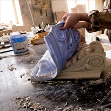Caucasian artist lifting mold from plaster