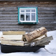 Firewood on sled in snow outside cabin