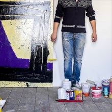 Caucasian artist holding paint roller near painting