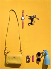 Purse and summer accessories on yellow background