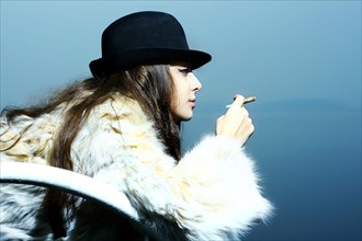 Portrait of glamorous woman wearing fur coat smoking cigarette