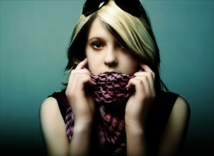 Portrait of serious Caucasian teenage girl holding scarf over mouth