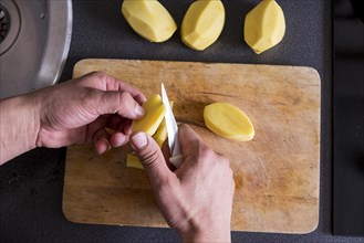 Caucasian hands cutting potatoes on cutting board