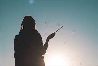 Silhouette of a woman waving bubble wand
