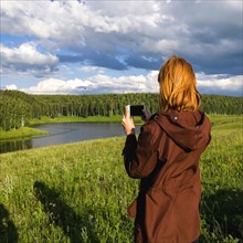 Woman photographing river with cell phone