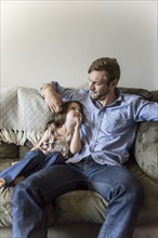 Father and daughter sitting on sofa