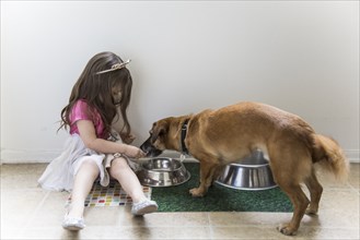 Caucasian girl feeding dog on floor