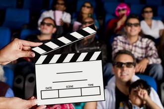 Clapperboard in front of Hispanic people in movie theater