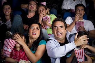 Frightened Hispanic family watching film in movie theater
