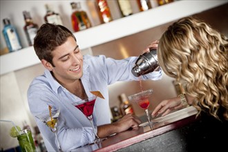 Hispanic bartender pouring cocktail for customer
