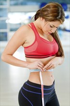 Hispanic woman measuring waistline