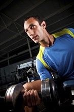 Hispanic man lifting weights in health club
