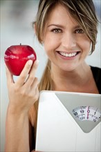 Hispanic woman holding apple and weighting scale