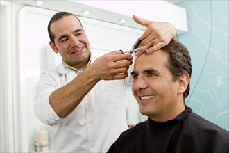 Hispanic man having hair cut in barber shop