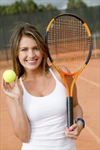 Hispanic woman holding tennis racquet and ball