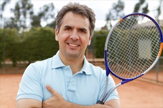 Hispanic man standing on tennis court with racquet