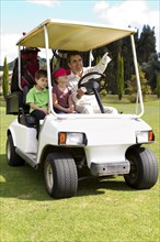 Hispanic father and children riding in golf cart