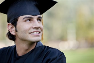 Smiling Hispanic graduate in cap and gown