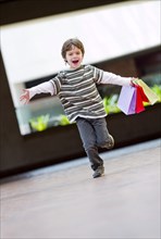Hispanic boy running with shopping bags