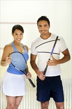 Hispanic couple holding squash racquets
