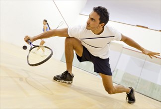 Hispanic couple playing squash