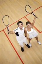 Hispanic couple raising squash racquets