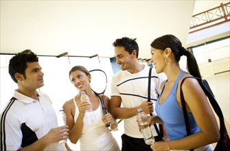 Hispanic couples on squash court drinking water
