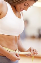 Hispanic woman measuring her waist in gym