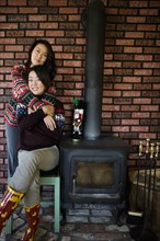 Chinese mother and daughter hugging near fireplace