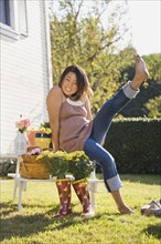 Chinese woman kicking up feet in garden