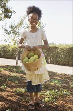 Mixed race girl holding basket of apples