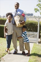 African father with groceries hugging children