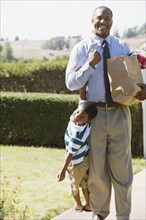 African father carrying groceries and son