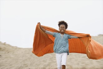Mixed race girl playing with blanket at beach