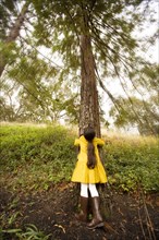 Mixed race girl hugging tree