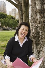 Chinese woman holding folder next to tree