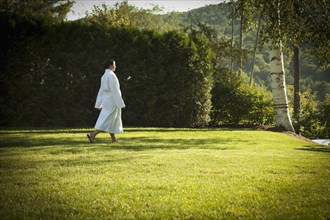 Woman walking across lawn in bathrobe