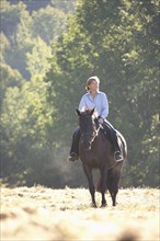 Caucasian woman riding horse in field