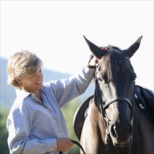 Caucasian woman petting horse