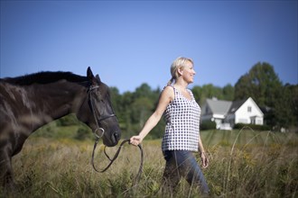 Caucasian woman leading horse through field