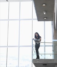 Asian businesswoman standing on internal office balcony