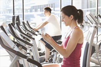 Woman on treadmill text messaging on cell phone