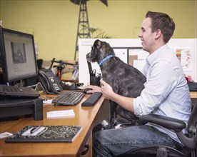 Caucasian man in office with dog sitting in lap