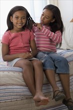 African American girl braiding sister's hair