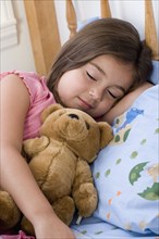 Hispanic girl sleeping with teddy bear