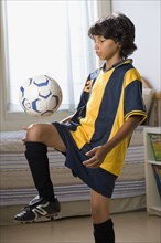 Mixed Race boy bounding soccer ball on knee